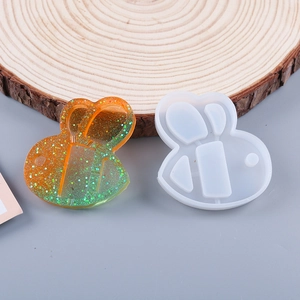 Detail of bee shaped silicone mold and gradient glitter resin pendant on wood base