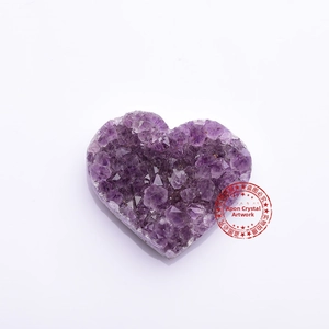 Macro shot of natural purple amethyst geode heart with dense sparkling crystal clusters