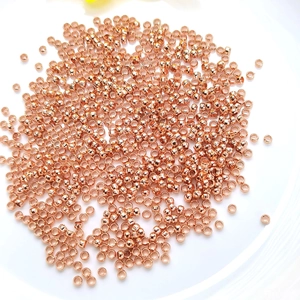 14K rose gold plated round spacer beads for DIY jewelry making scattered on white plate