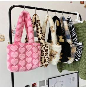 Close-up of five plush tote bags in heart, leopard, and floral prints hanging on a rack