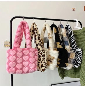 Detail showing various patterns of soft faux fur tote bags hanging on a display rack