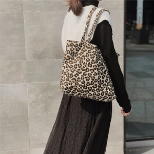 Close-up of leopard print canvas tote bag with wide shoulder straps on a female model