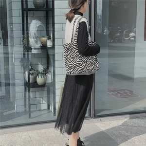 Detail view of large zebra print canvas tote bag shown from a casual side-wearing angle