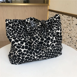 Close-up of black and white geometric pattern tote bag on a neutral stone background