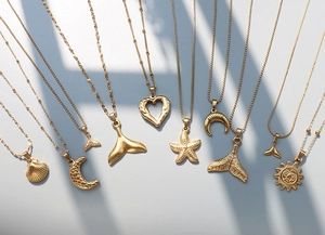 Detail of 18k gold plated stainless steel ocean charms with seashell and starfish motifs