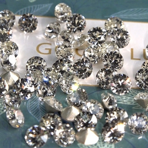 Macro shot of loose round cut brilliant gemstones scattered over a patterned surface
