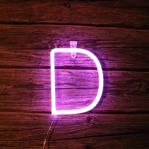 Close-up of purple LED neon letter D on a rustic wood wall for holiday wall decoration