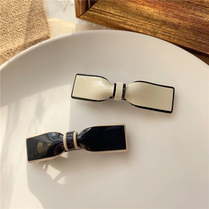 Elegant bow hair clips set in black and cream acrylic on a white ceramic tray