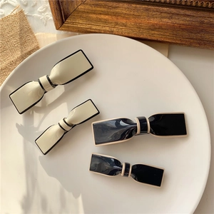 Detail showing elegant black and white bow hair clips on a ceramic plate with lace