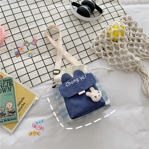 Detail of blue and white checkered bucket bag featuring a 3D rabbit doll and drawstring