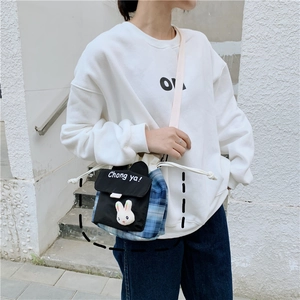Detail of blue checkered bucket bag featuring a cute 3D plush rabbit and drawstring closure