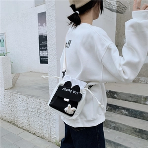 Outdoor shot of a black and white canvas bucket bag with cute rabbit ears and charm