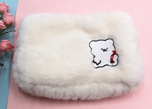 Détail de la trousse de maquillage en peluche blanche avec broderie d'ours et texture douce