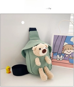 Detail of green canvas kids chest bag featuring a cute beige plush bear ornament