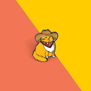 Cute enamel orange cat pin featuring a cowboy hat and scarf on a vibrant split background