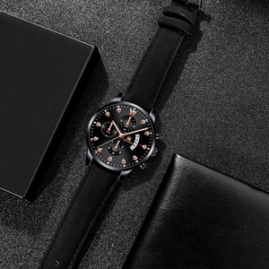 Detail of men's business watch with black dial, rose gold markers and leather strap