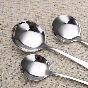 Set of three polished stainless steel round soup spoons in various sizes on a beige mat