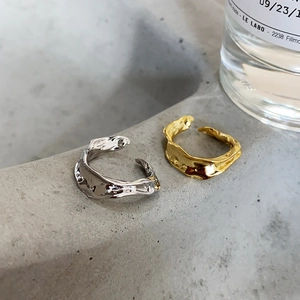 Detailed view of minimalist lava texture open rings in gold and silver on stone