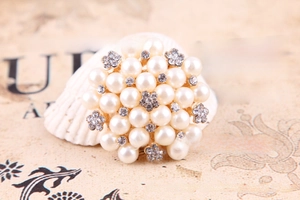 Macro shot of a floral pearl brooch with sparkling rhinestones on a vintage background