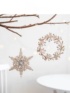 Close-up of champagne gold glitter snowflake and wreath ornaments on branches