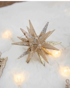 Detail of glittery gold and silver star ornaments on white faux fur with warm string lights