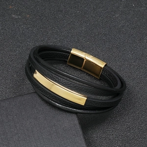 Macro detail of multi-layer black leather men's bracelet with golden magnetic metal clasp