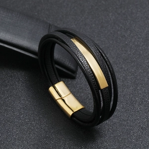 Close-up of black multilayer leather bracelet with gold metal clasp on leather background