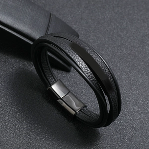 Macro detail of multi-layer black leather bracelet with dark metal clasp and blank plaque