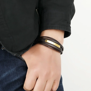 Men's brown braided leather bracelet with a gold metal bar accent on male model's wrist