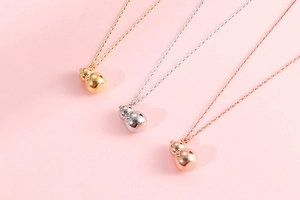Gourd-shaped necklaces in gold, silver, and rose gold finish shown on a pink backdrop