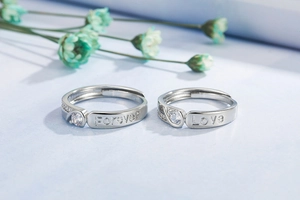 Macro shot of silver couple rings with Forever Love engraving and small zircons