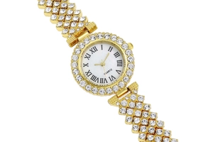 Detail of gold quartz watch featuring Roman numerals and sparkling rhinestone bezel