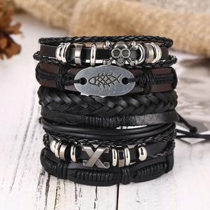 Close-up of men's layered leather bracelets with punk skull and fishbone charms