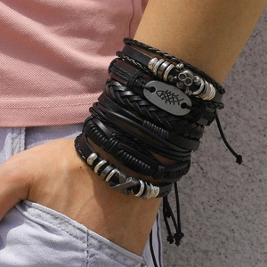 Detail of layered black leather bracelets featuring silver skull and fishbone metal charms