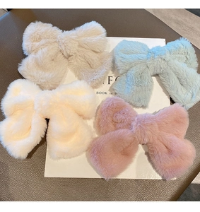 Close-up of soft plush bow hair clips in cream, blue, yellow, and pink colors