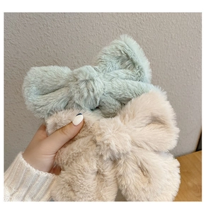 Close-up of soft plush bow hair clips in mint green and apricot with fuzzy texture
