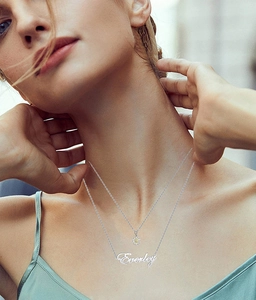 Close-up of double-layer silver name necklace with flower charm and Everley pendant