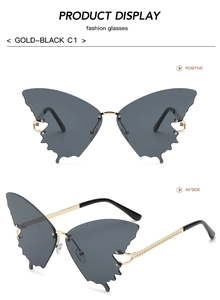 Detail view of butterfly rimless sunglasses with gold braided temples and dark grey lenses