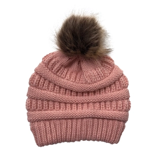Detail of pink knitted beanie featuring a fluffy brown faux fur pompom on top