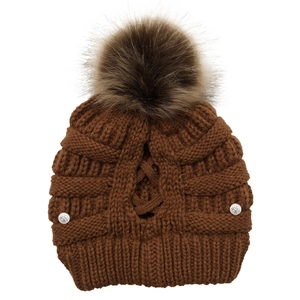 Close-up of brown knit beanie with faux fur pompom and rose engraved silver buttons