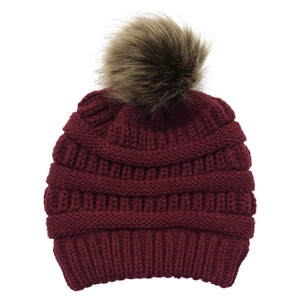 Close-up of wine red knitted beanie featuring a fluffy faux fur pompom and cross band
