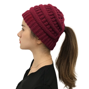 Detail of burgundy knitted ponytail beanie showing the coarse ribbed texture and top opening