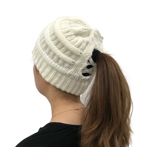 Detail view of the white cable knit beanie with a functional opening for ponytails