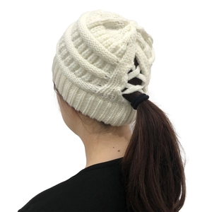 White knit beanie detail showing the functional ponytail hole design and soft texture