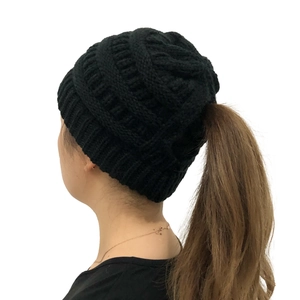 Close-up of black cable knit beanie with ponytail hole and stretch texture details