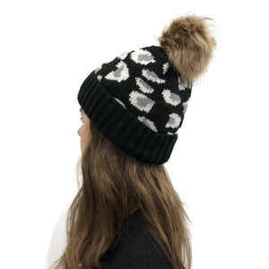 Detail shot of leopard print knit beanie with a fluffy brown faux fur pom pom decoration