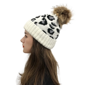 Detail of leopard print knit hat with fluffy faux fur pompom and thick ribbed cuff