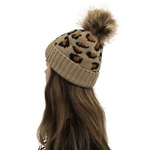 Close-up of leopard print knit beanie with fuzzy pompom and soft textured fabric detail