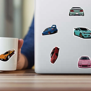 Waterproof JDM car stickers on a laptop and mug showing classic racing car designs