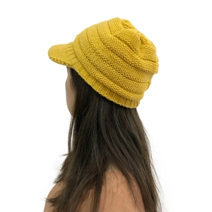 Side view of winter yellow knitted hat with brim showing warm ear protection texture